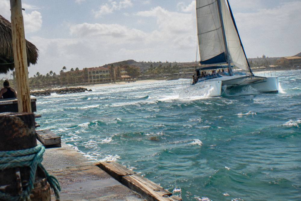 Catamaran heel under full sail in fresh trade winds off the Aruba coast at late afternoon